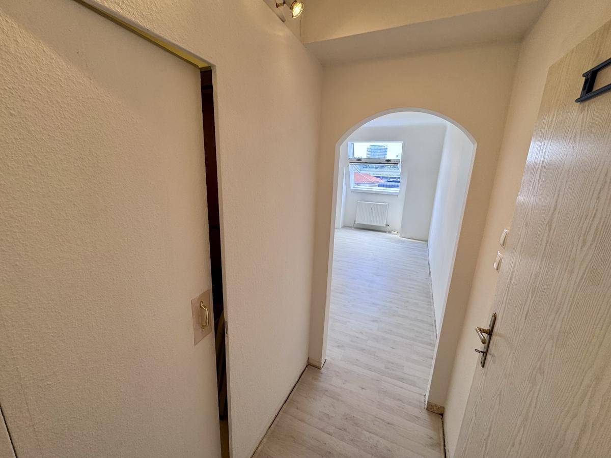 Heller Flur mit Laminatboden und einem Bogen, der zu einem weiteren Raum führt.