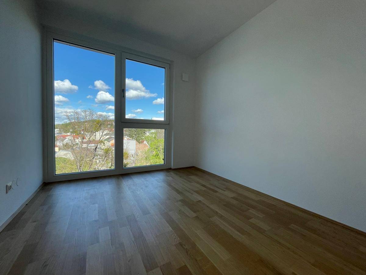 Helles Zimmer mit Parkettboden und großem Fenster, das einen weiten Blick bietet.