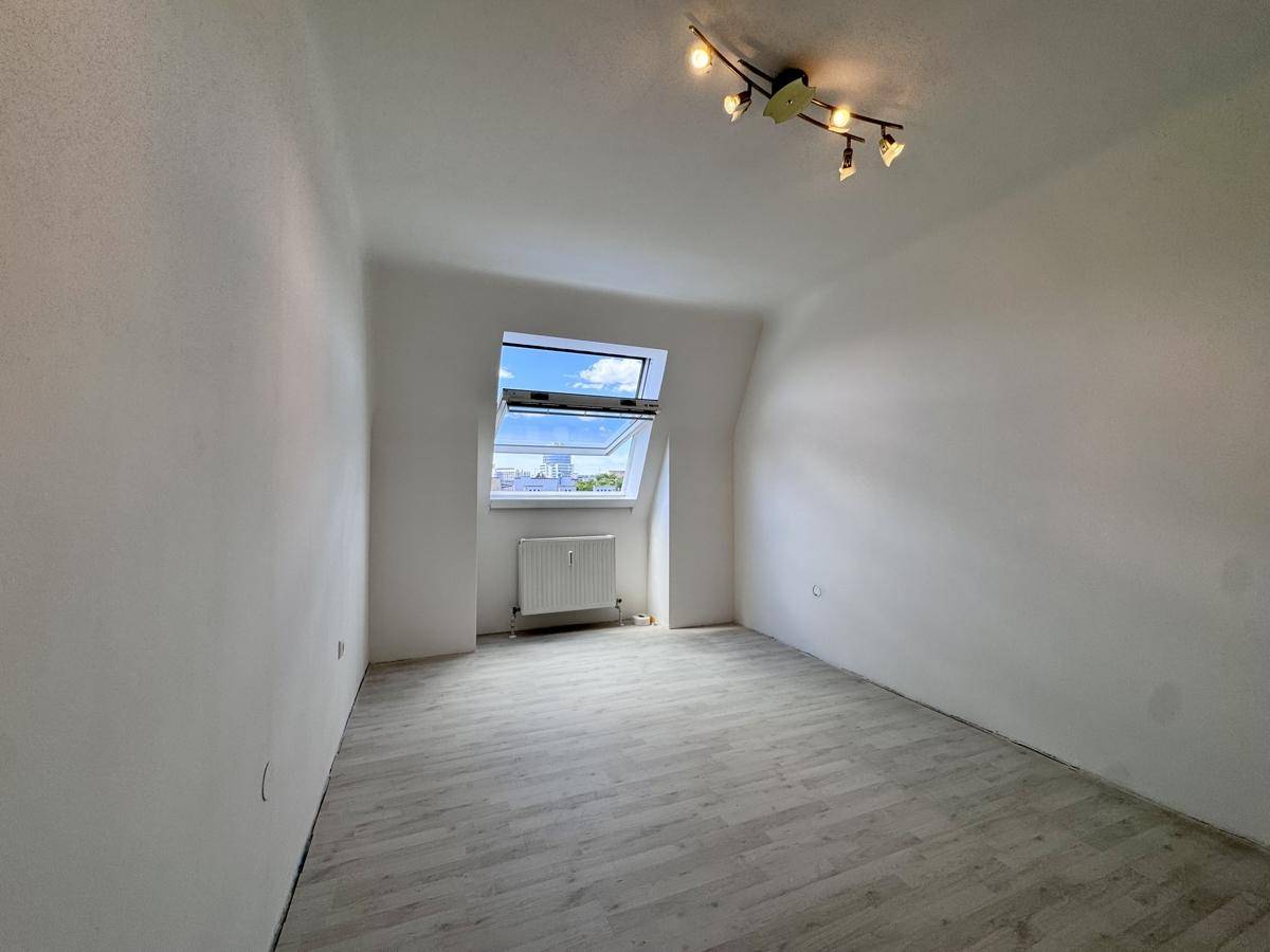 Geräumiges Schlafzimmer mit hellem Laminatboden, Dachfenster und Deckenbeleuchtung.