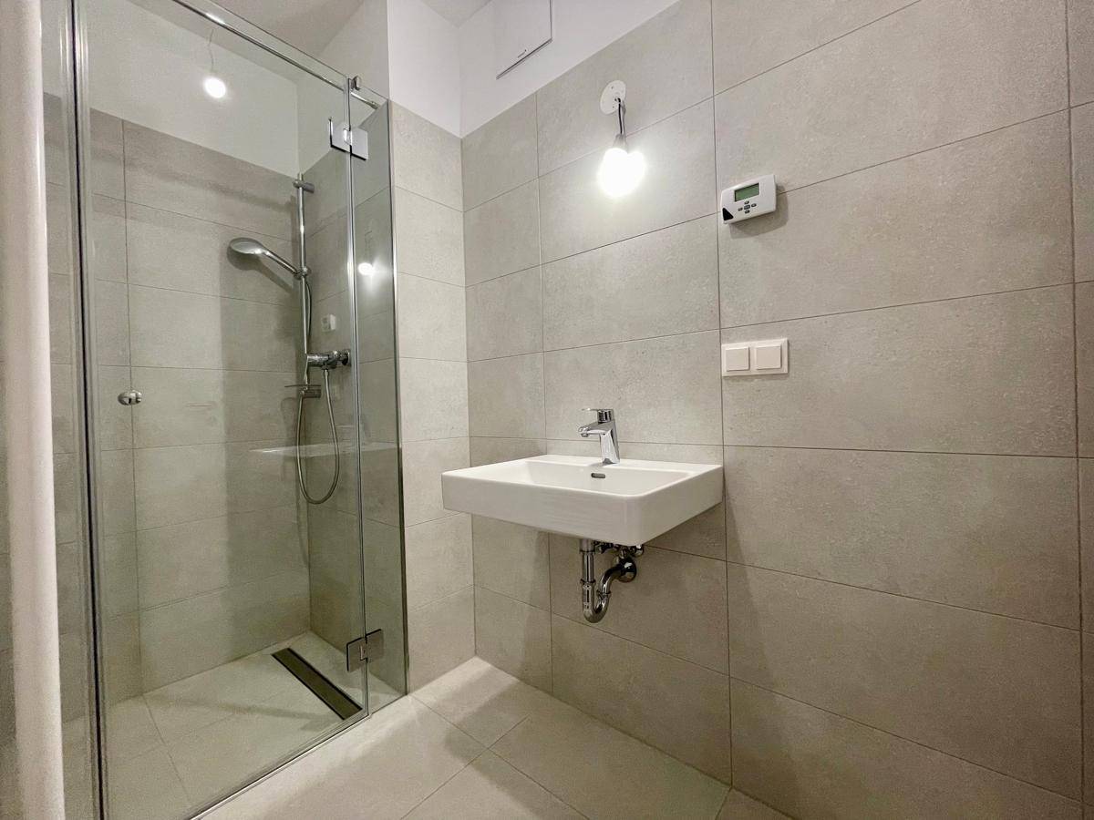 Modernes Badezimmer mit begehbarer Dusche, Glasabtrennung und einem einzelnen Waschbecken.