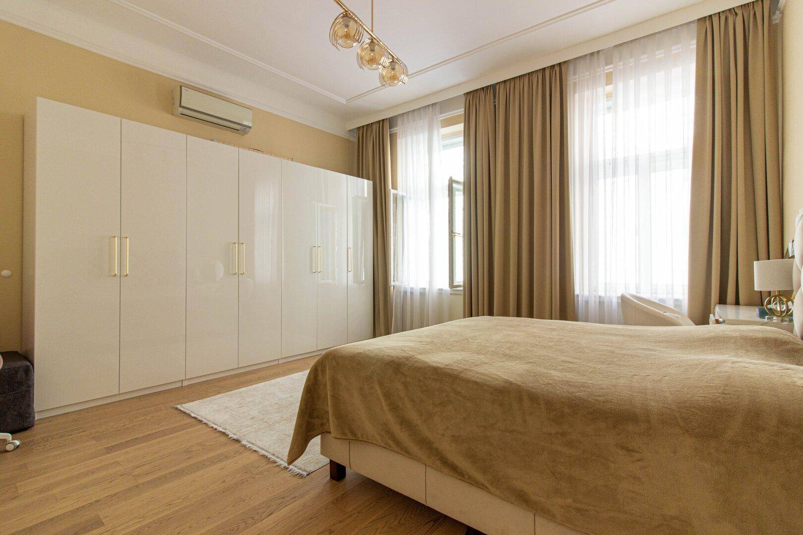 Schlafzimmer mit großem Einbauschrank, Parkettboden und Klimaanlage für angenehmes Raumklima.