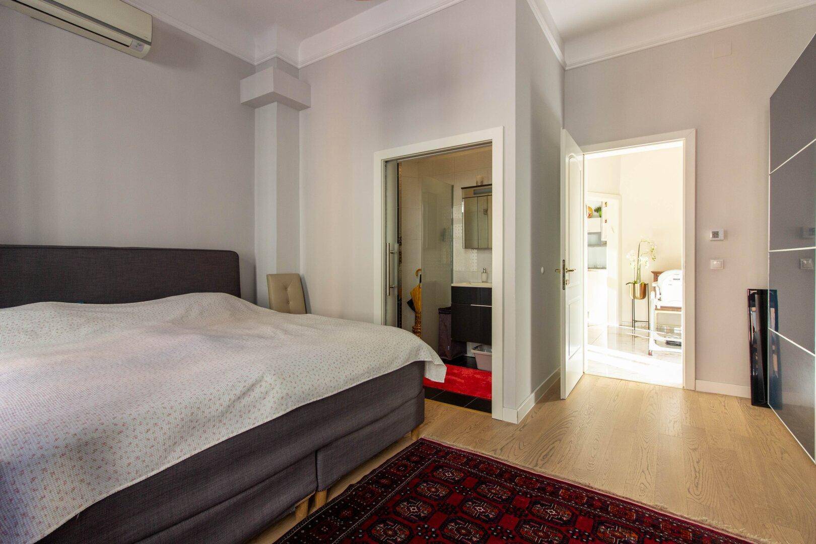 Schlafzimmer mit Parkettboden und direktem Zugang zu einem modernen Badezimmer mit Dusche.