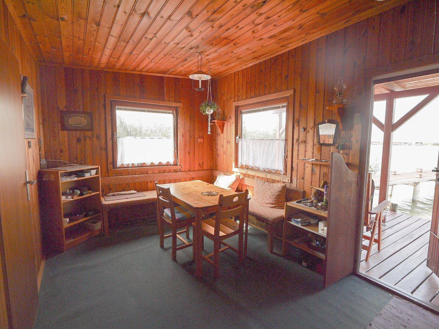 Gemütlicher Essbereich mit Holzwänden und direktem Zugang zur Seeterrasse.