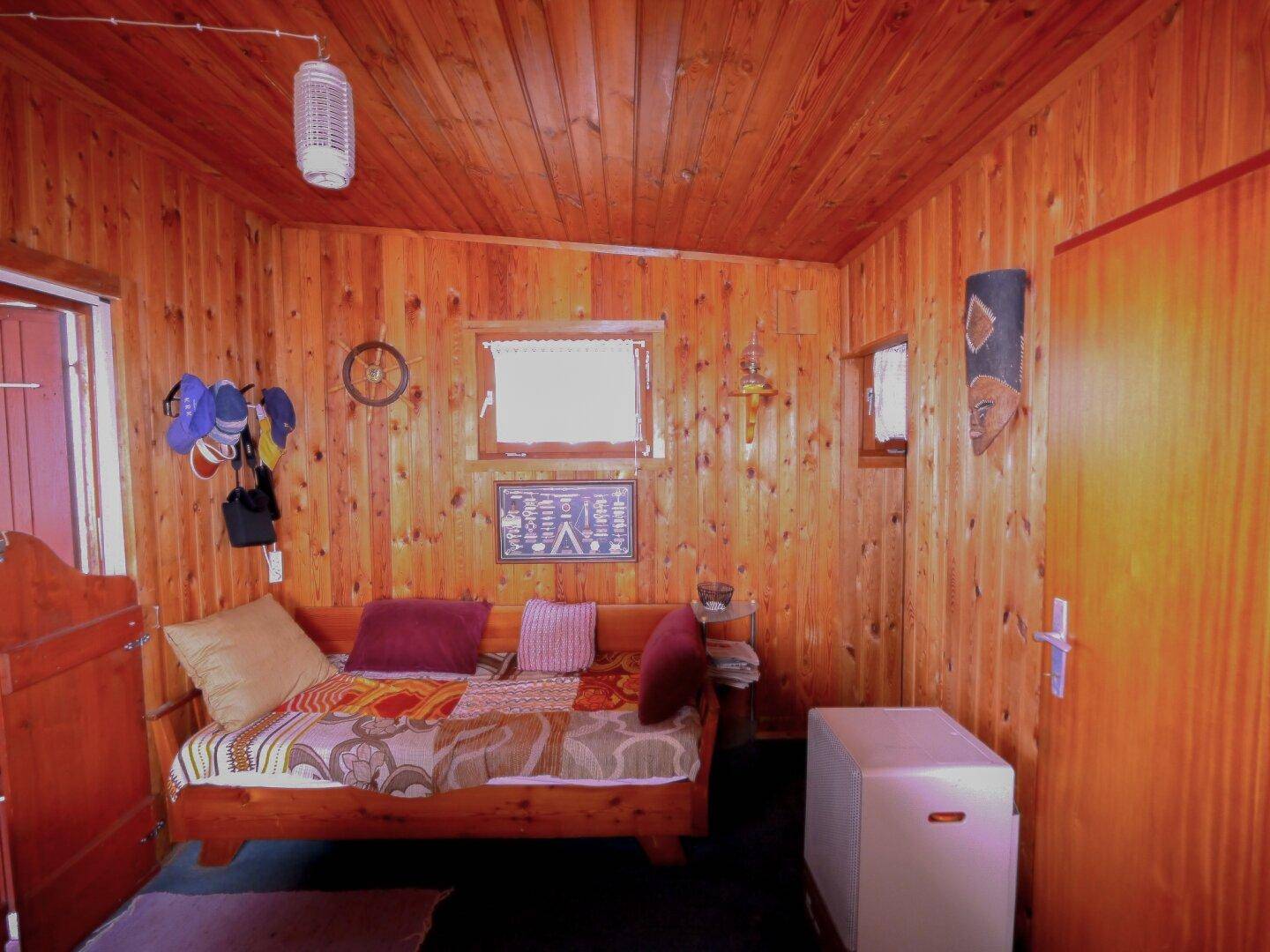 Wohnbereich mit Holztäfelung, Tagesbett und rustikaler Dekoration.