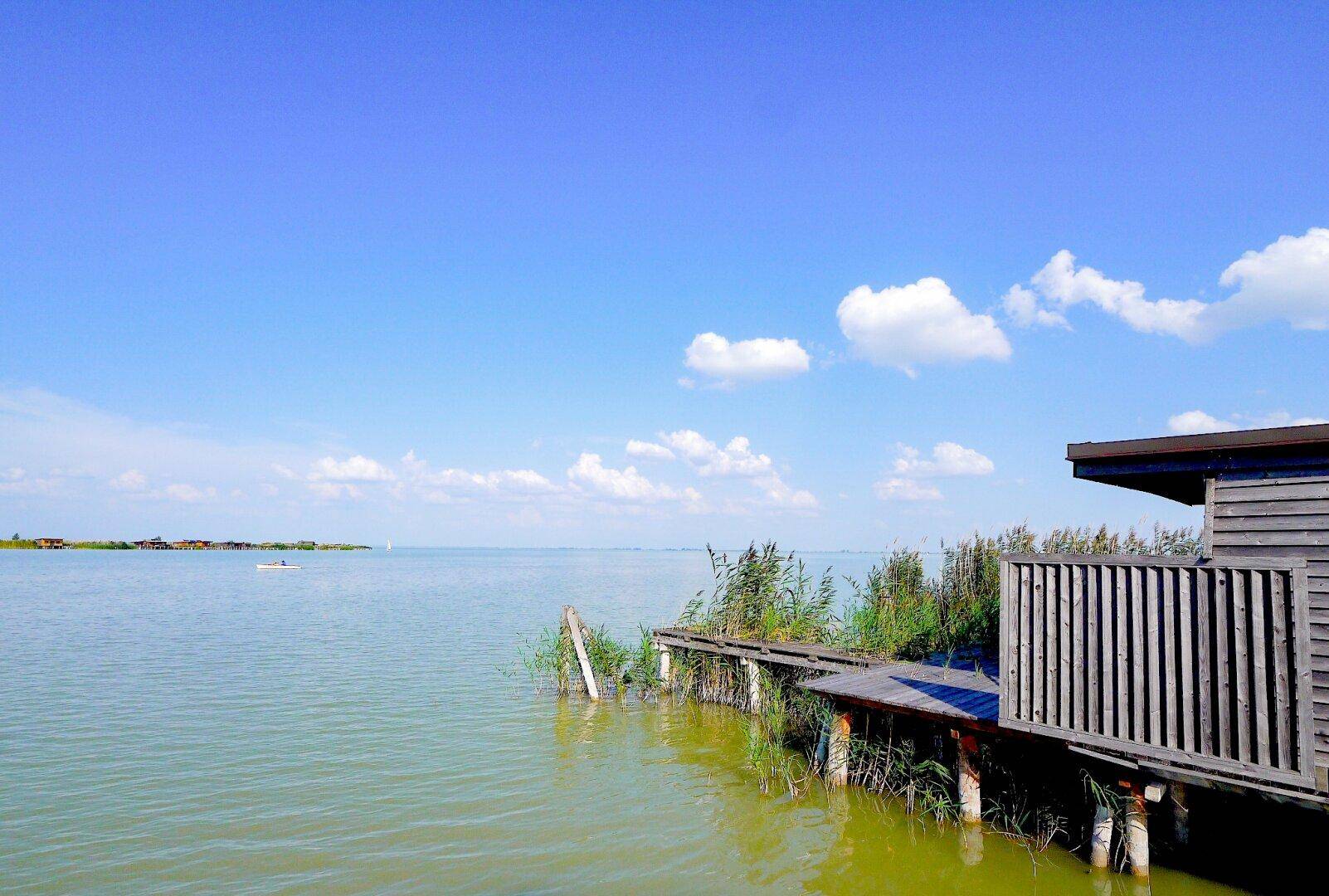 Seeseitiges Holzhaus auf Stelzen mit angrenzender Holzterrasse und Blick auf das Wasser.