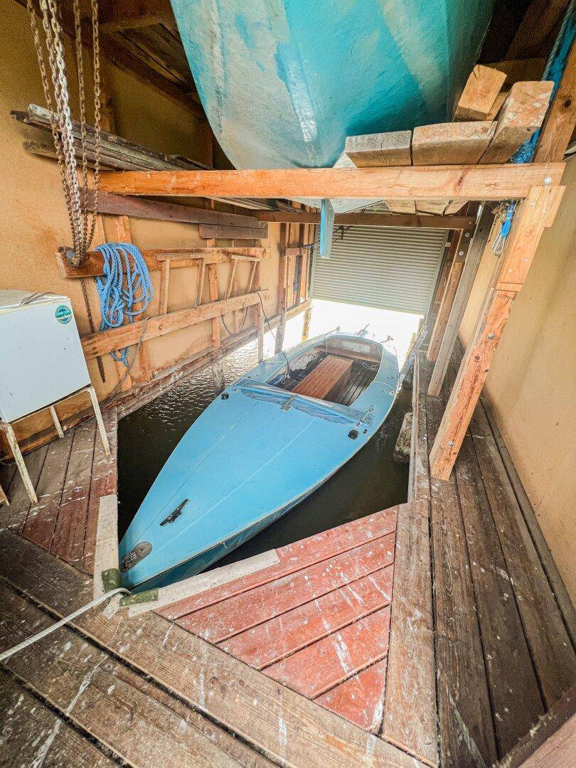 Bootsgarage mit einem blauen Boot im Wasser und einem weiteren Boot darüber gelagert.