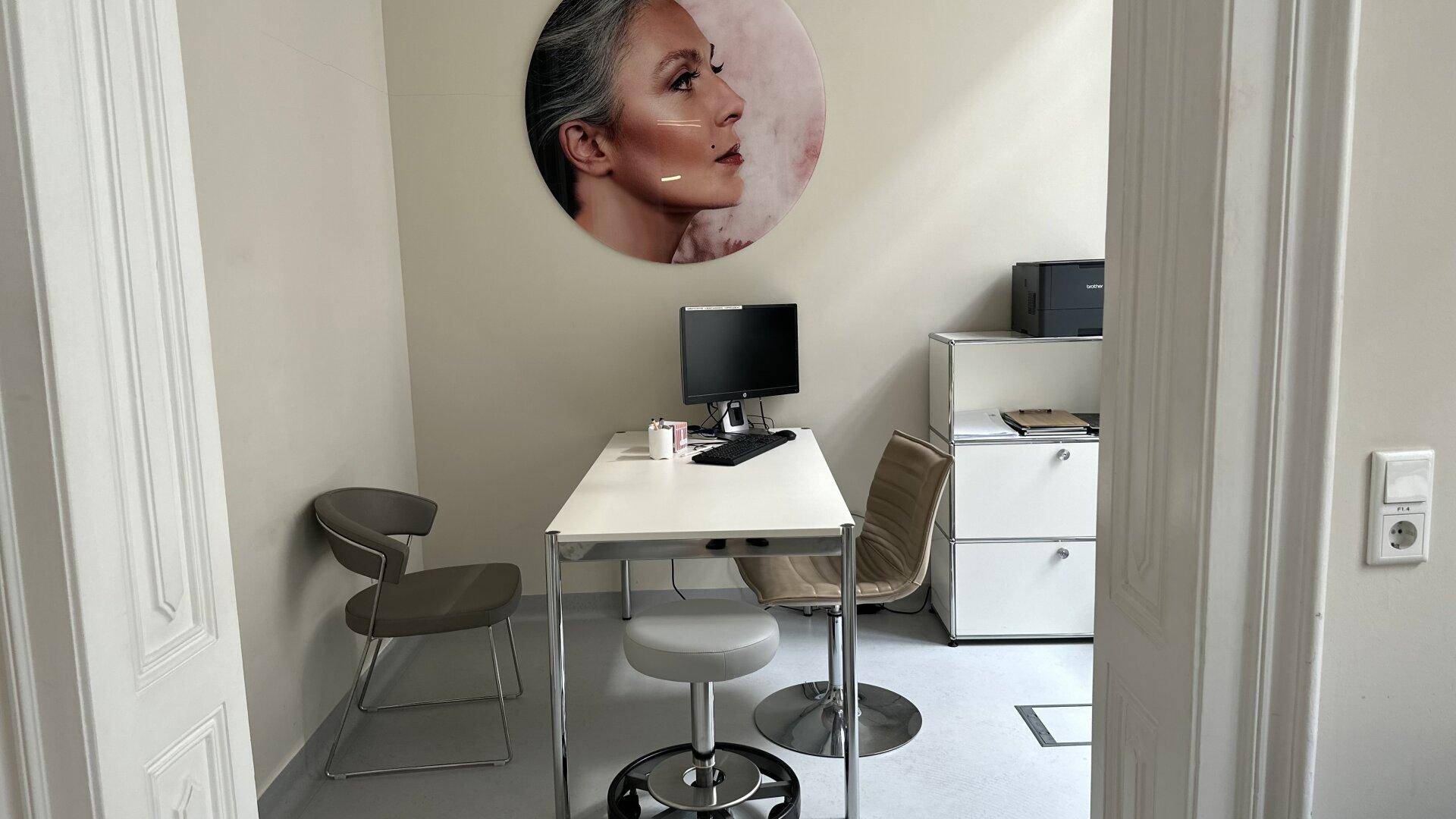 Kleines Büro mit Schreibtisch, Bürostuhl und einem Bild an der Wand.
