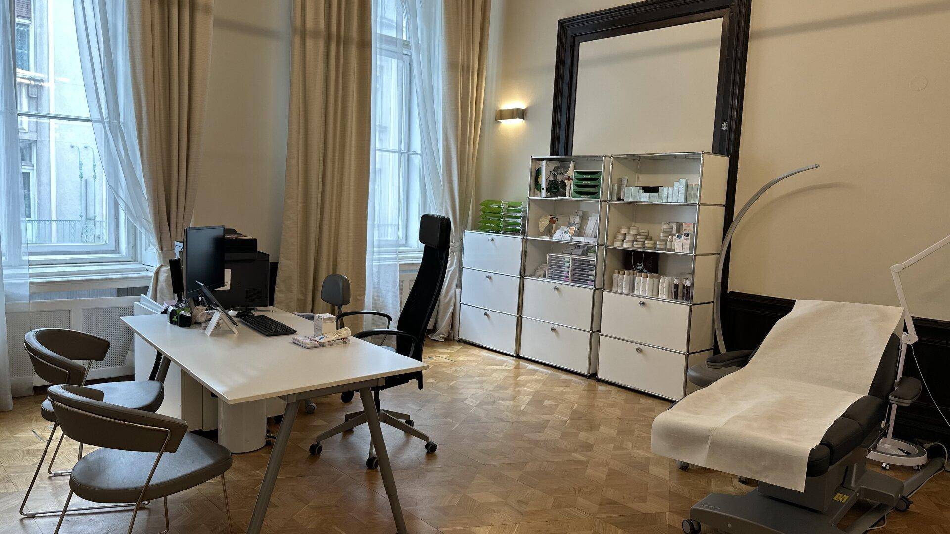 Geräumiges Büro mit Schreibtisch, Bürostuhl, Regalen und einer Behandlungsliege.