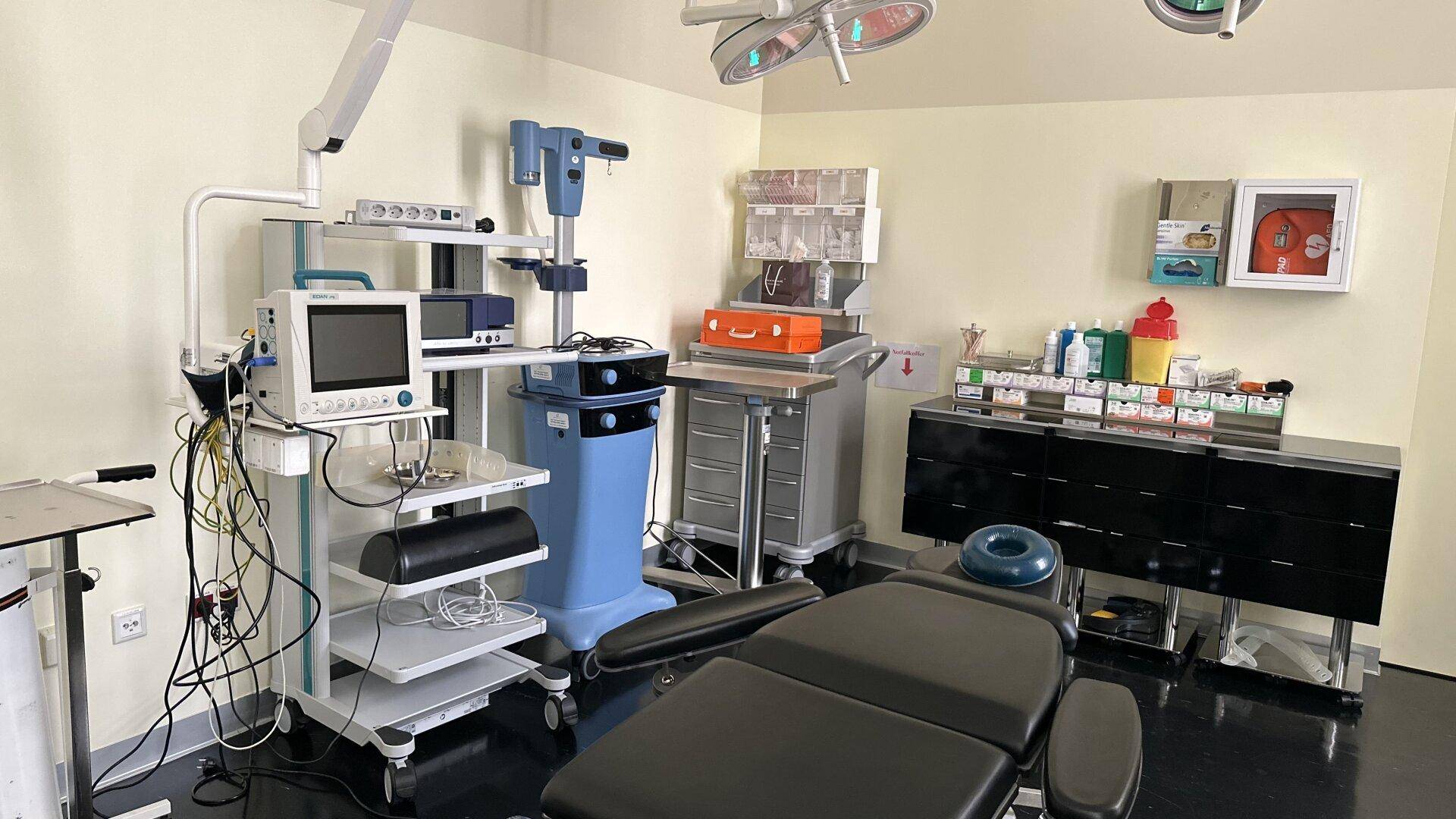 Operationssaal mit medizinischen Geräten, OP-Leuchten und dunklem Boden.