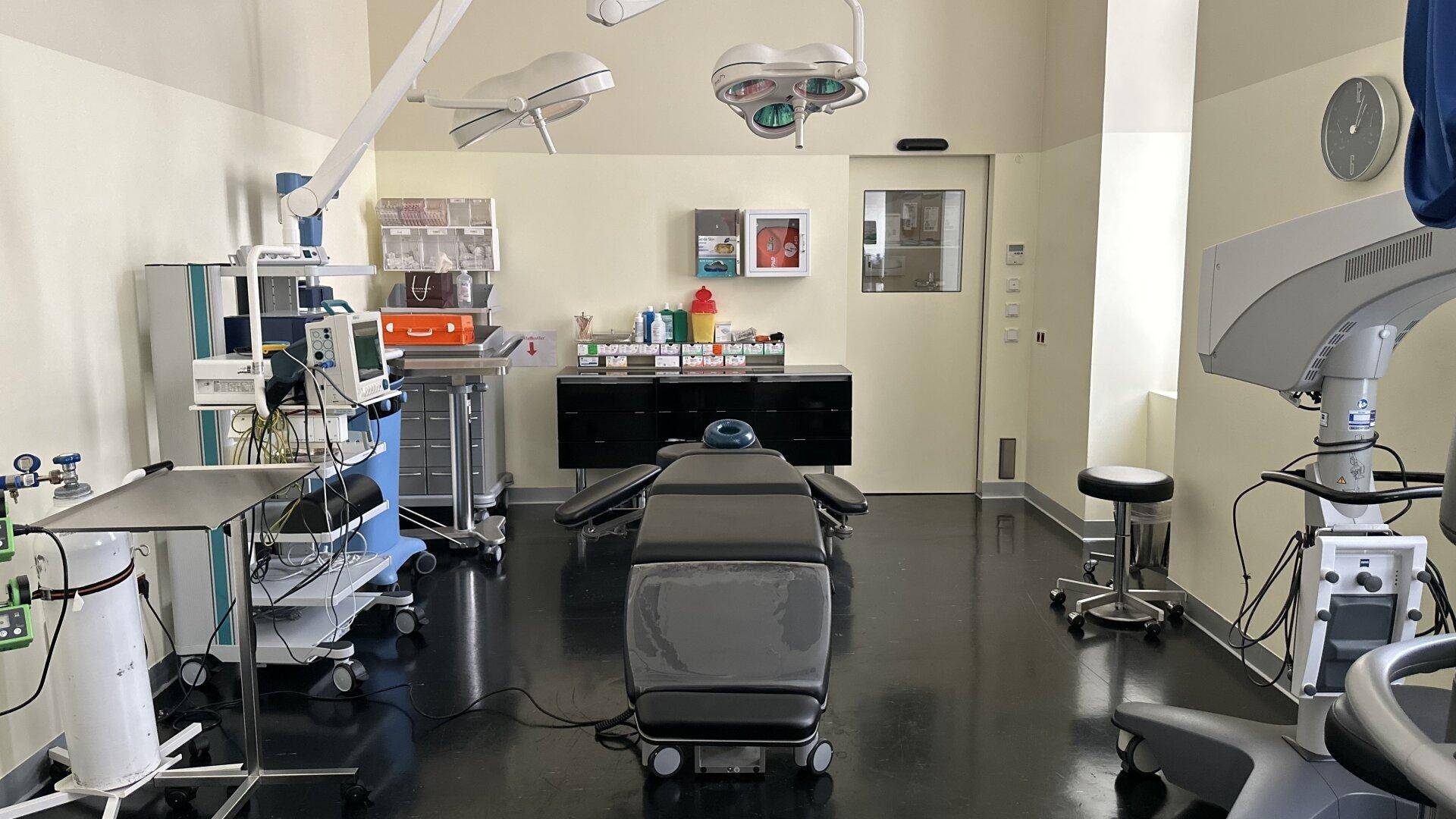 Operationssaal mit medizinischen Geräten, OP-Leuchten und dunklem Boden.