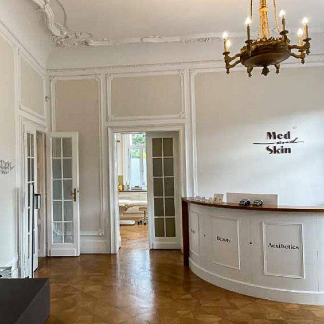 Detailansicht des Empfangsbereichs mit Rezeptionstheke, Stuckelementen und Holztüren.