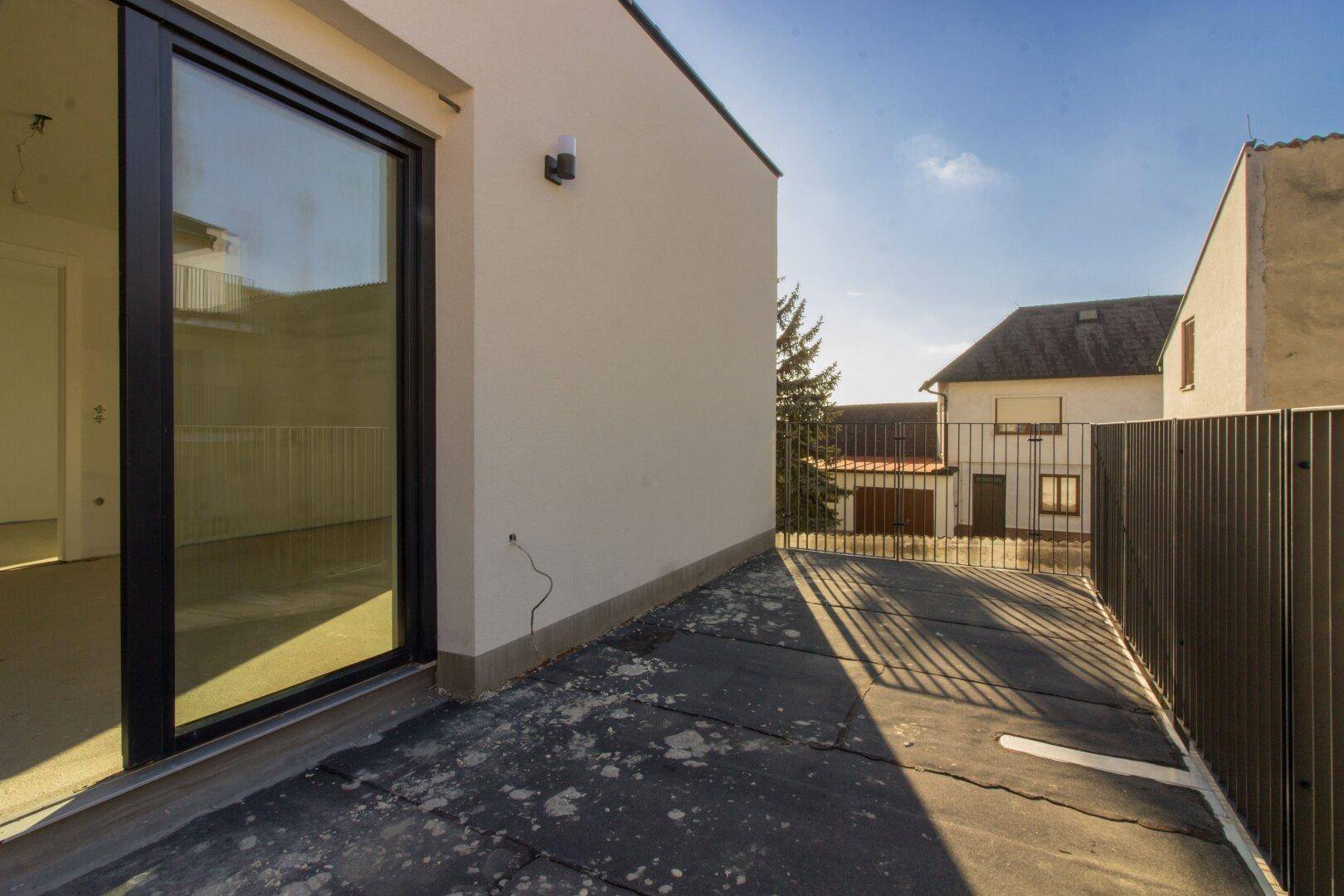 Sonniger Außenbereich mit großer Glastür und Blick auf die umliegenden Gebäude.