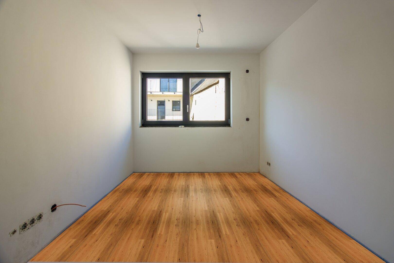 Kleinerer Raum mit neuem Holzboden und Fenster, ideal als Schlafzimmer oder Büro.