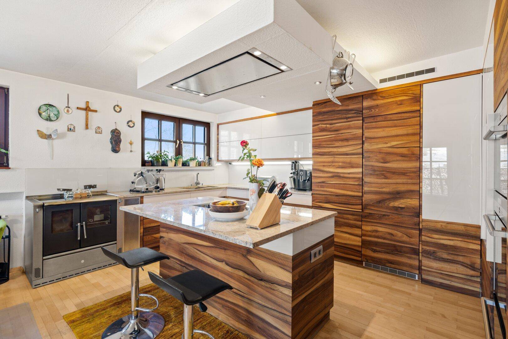 Moderne Küche mit Holz- und Hochglanzfronten, Kücheninsel und integrierten Geräten.