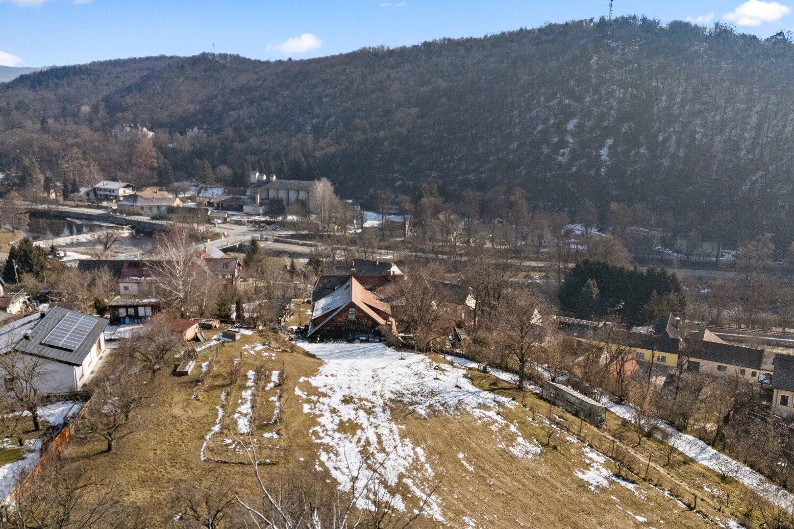 Luftaufnahme des Anwesens mit Haus und umliegender Hügellandschaft, teilweise schneebedeckt.