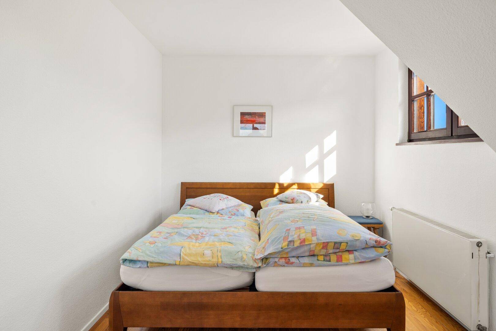 Helles Schlafzimmer mit zwei Einzelbetten, Holzboden und Dachschräge.