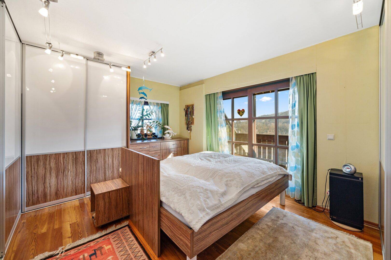 Geräumiges Schlafzimmer mit Holzboden, Einbauschränken und Zugang zum Balkon.