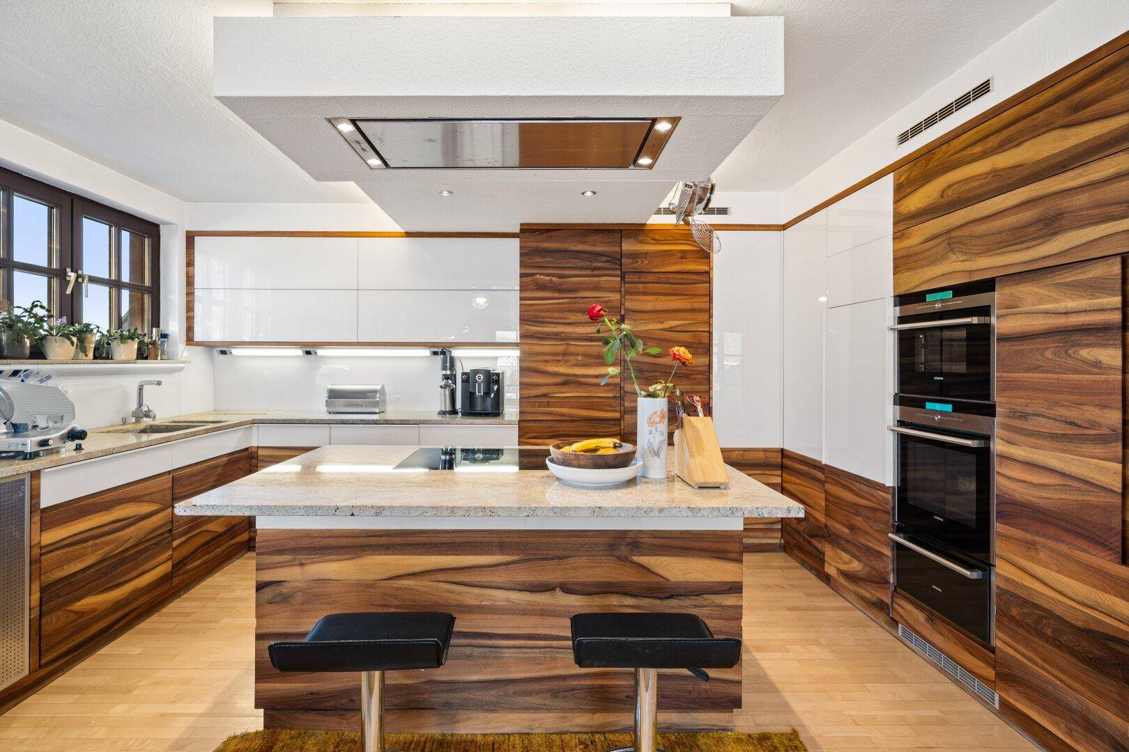 Moderne Küche mit Holz- und Hochglanzfronten, Kücheninsel und integrierten Geräten.