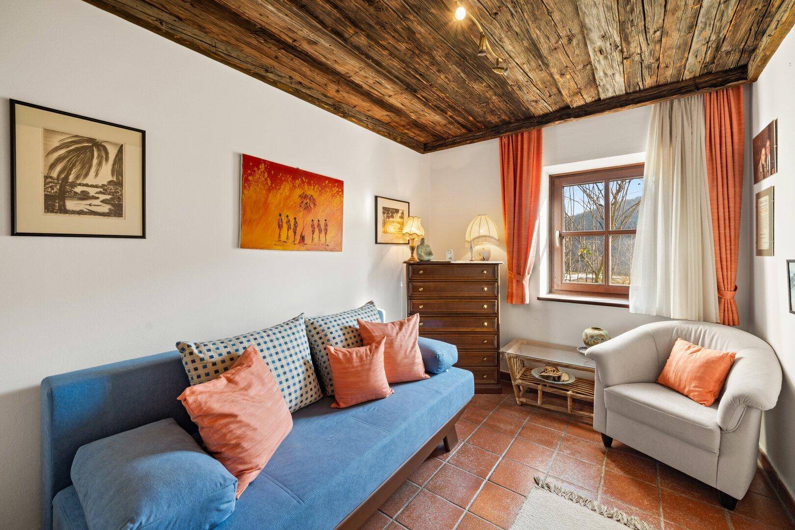 Gemütliches Gästezimmer mit Holzbalkendecke, Terrakottafliesen und farbenfroher Dekoration.
