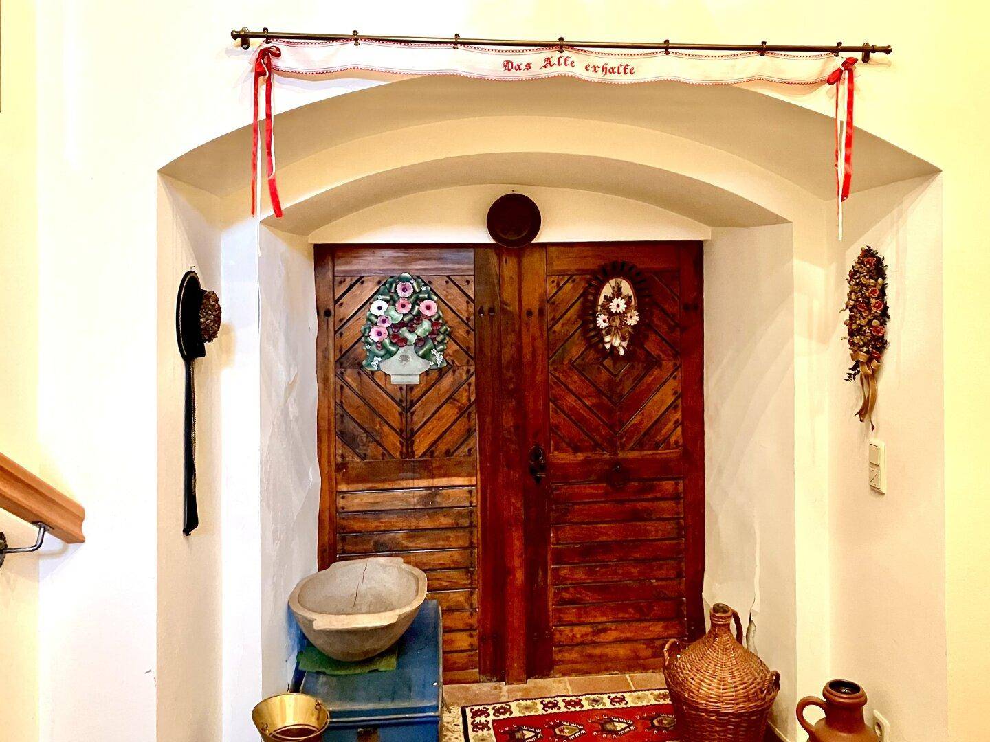 Rustikaler Eingangsbereich mit verzierten Holztüren und traditioneller Dekoration.