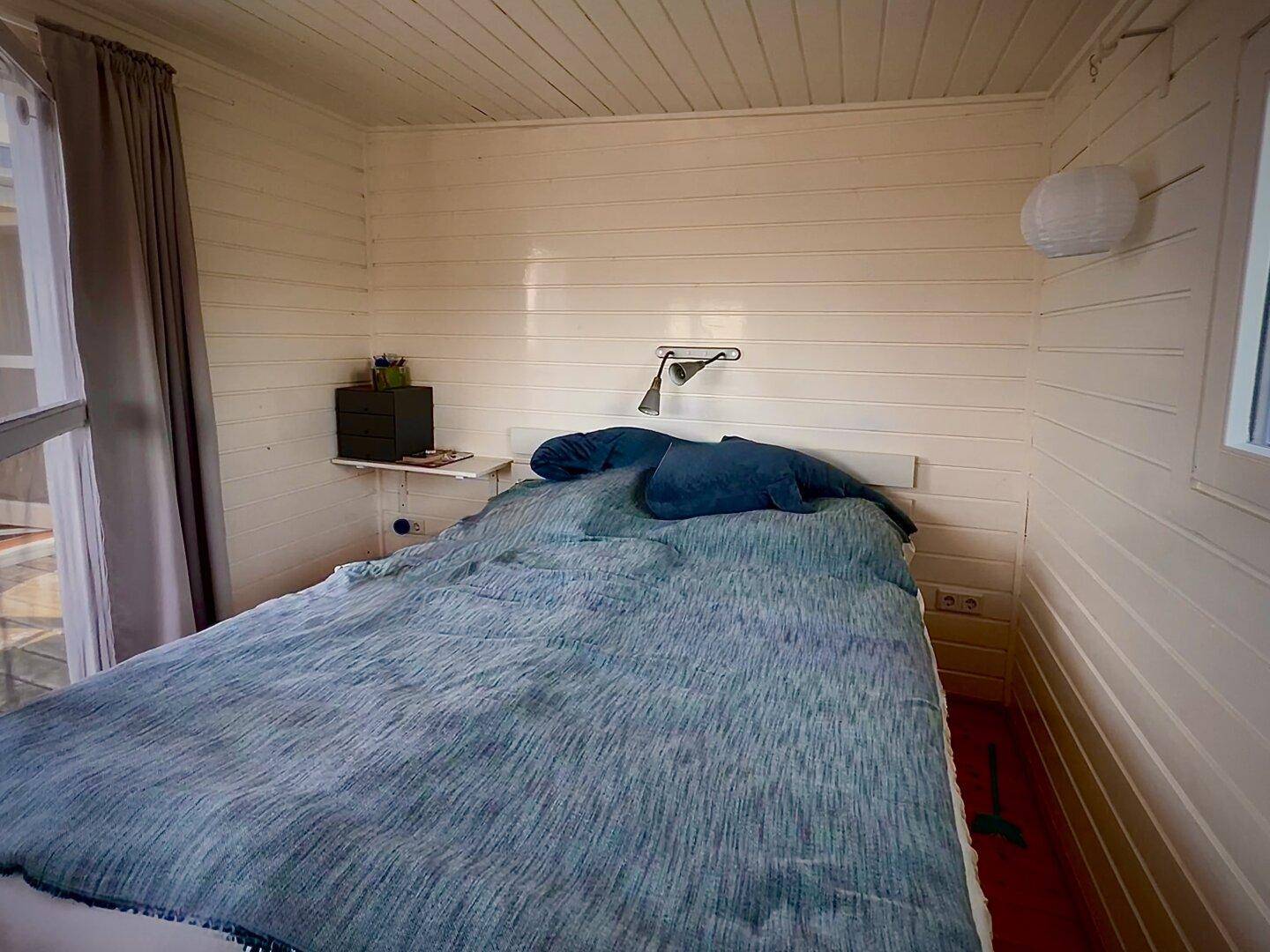 Schlafzimmer mit gemütlichem Bett, Holzwänden und Zugang zur Terrasse für frische Luft.