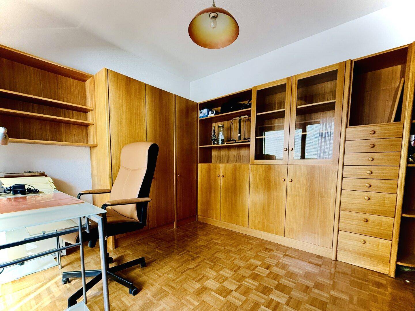 Arbeitszimmer mit umfangreichen Holzschränken und Regalen, ideal für Home-Office.