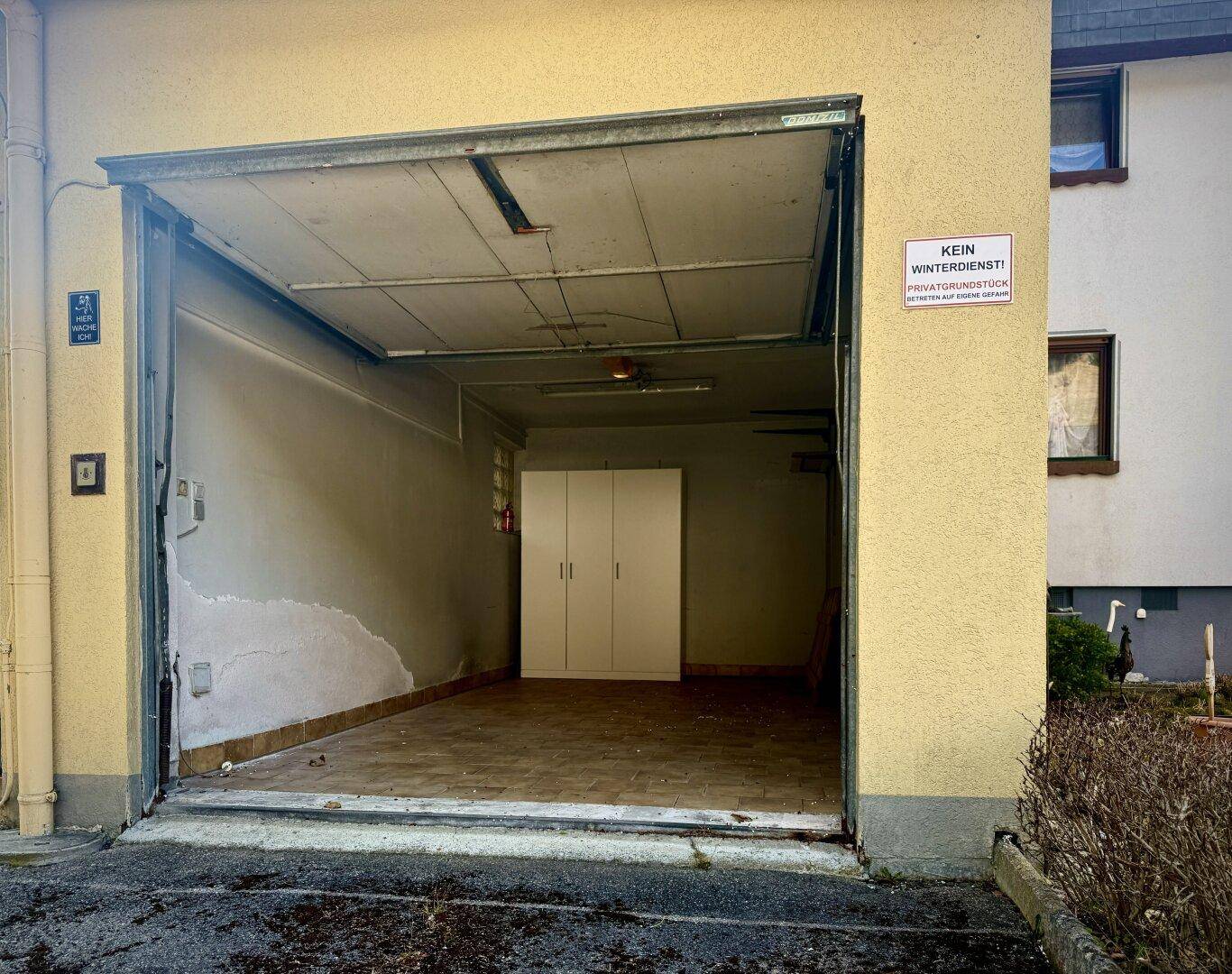 Geräumige Garage mit offenem Tor, bietet Platz für ein Fahrzeug und Lagerung.