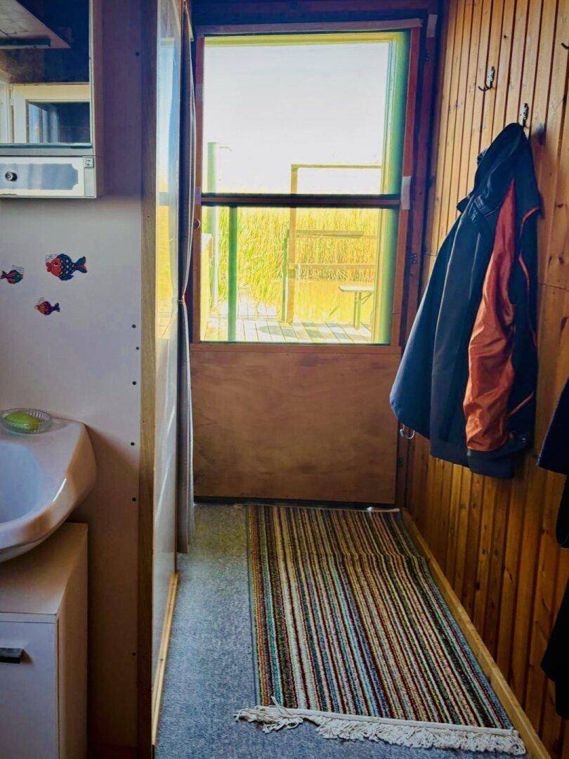 Kleiner Eingangsbereich mit Waschbecken, Spiegelschrank und Garderobenhaken.