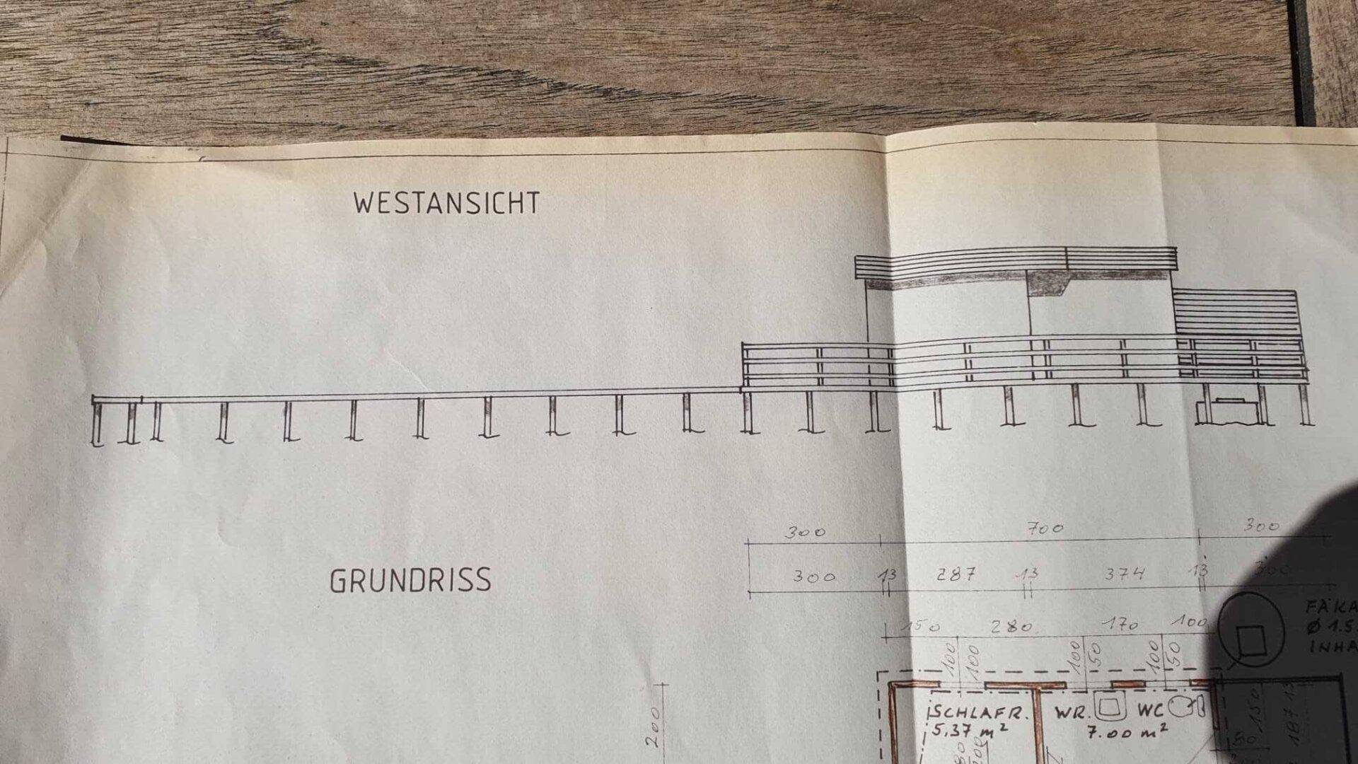 Westansicht des Gebäudes und ein Teil des Grundrisses mit Schlafzimmern und WC.