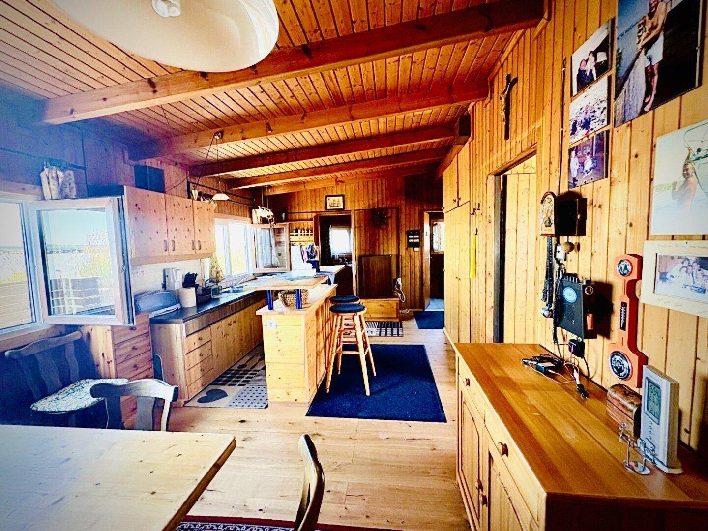 Offener Wohn- und Essbereich mit viel Holz, einer Kücheninsel und rustikalem Charme.