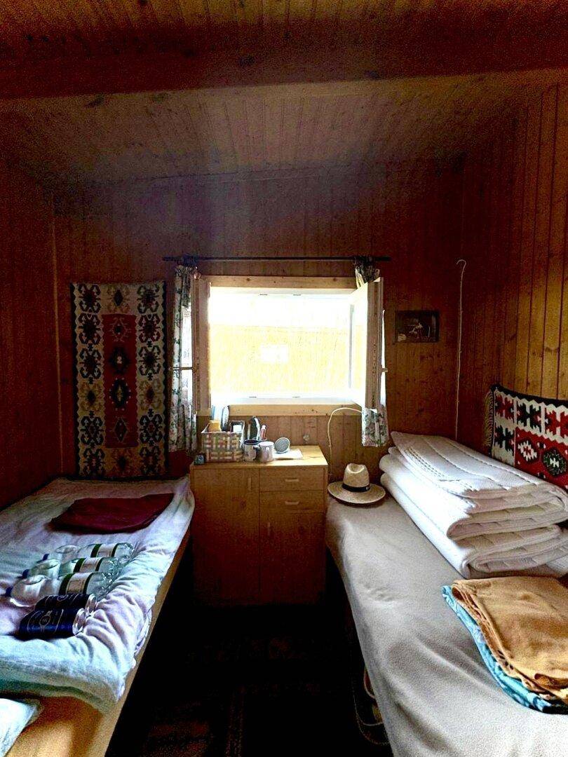 Schlafzimmer mit zwei Einzelbetten, Holzverkleidung und einem Fenster mit Blick ins Grüne.