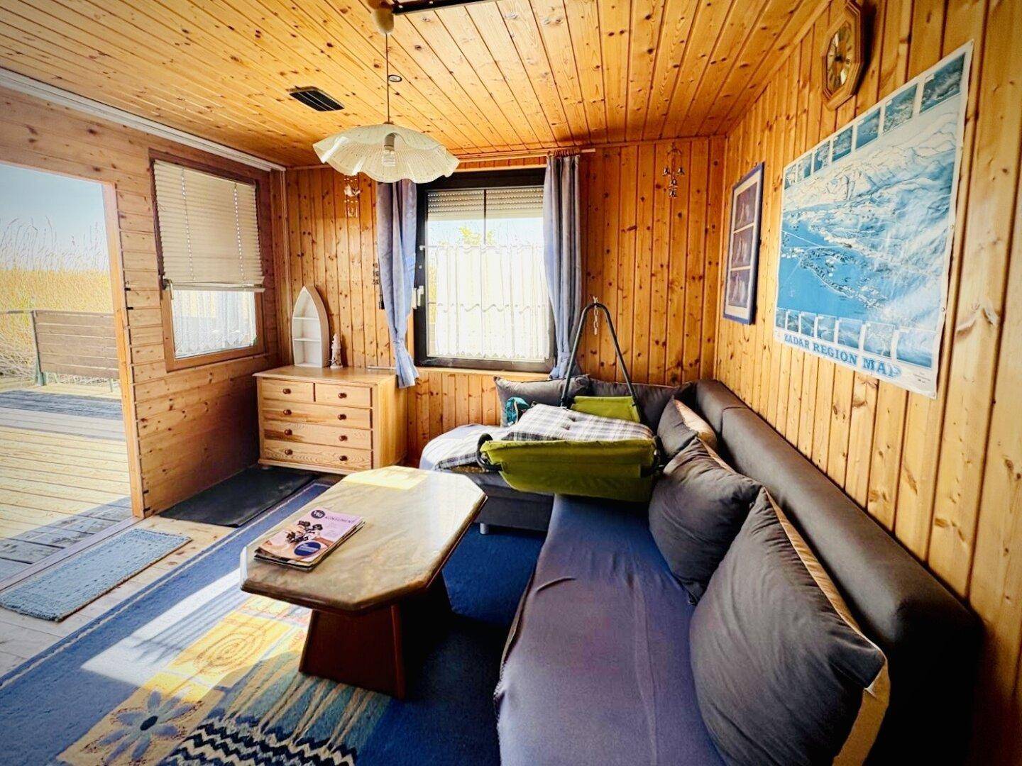 Gemütliches Wohnzimmer mit Holzverkleidung, Sofa, Couchtisch und Blick nach draußen.