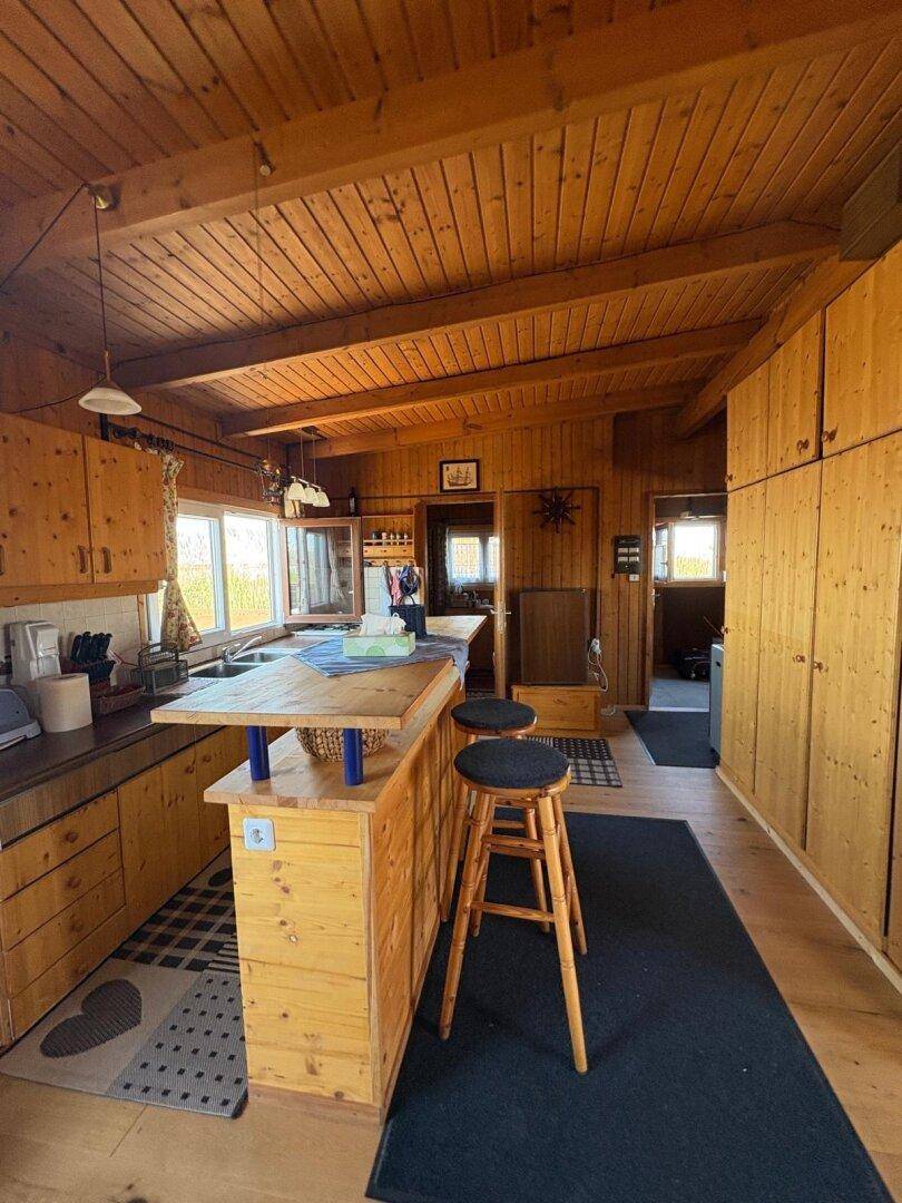 Gemütliche Holzküche mit einer Kücheninsel, Barhockern und viel Stauraum in den Schränken.