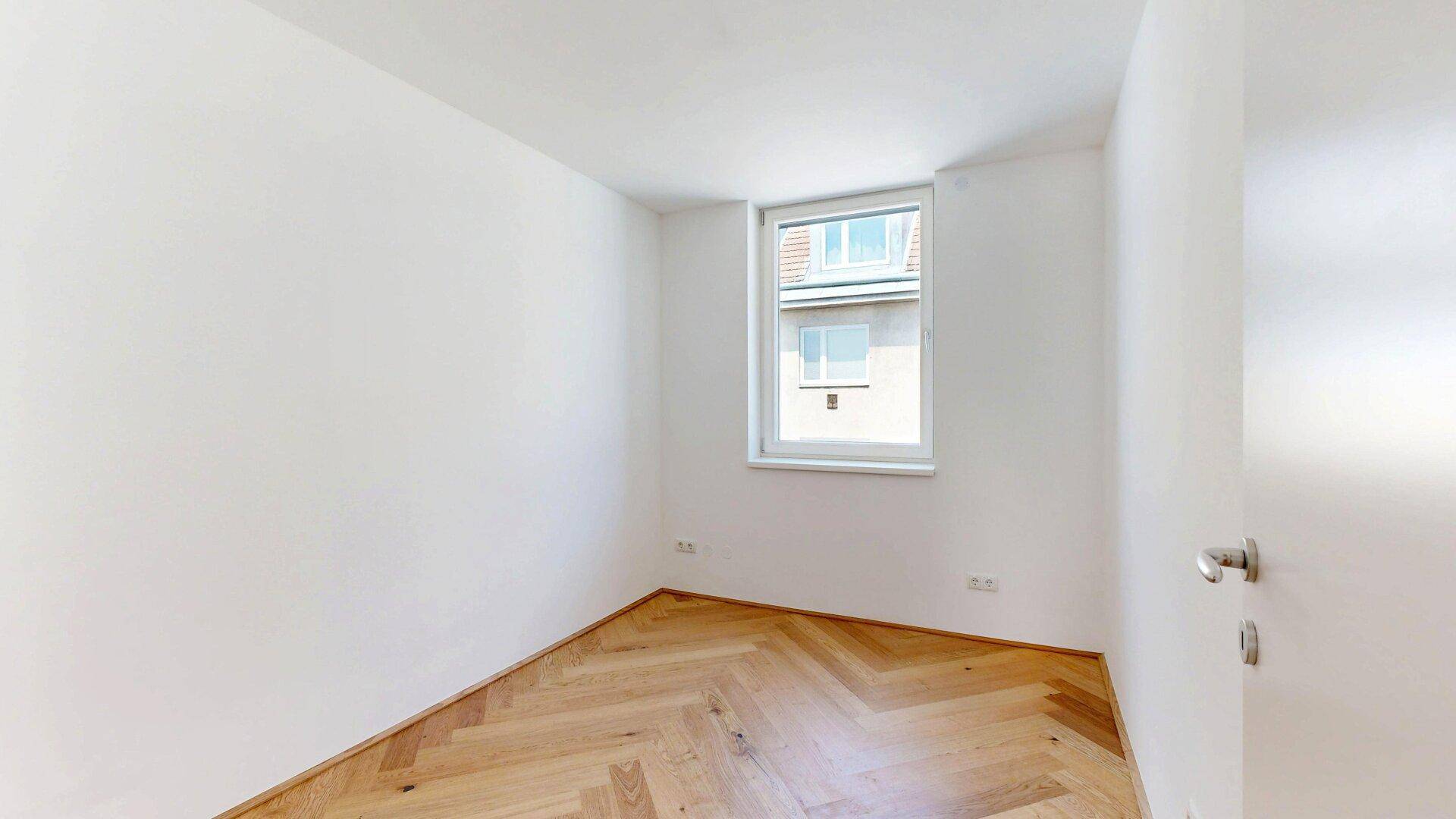 Helles Zimmer mit Fischgrätparkett und Fenster, ideal als Kinderzimmer oder Büro.