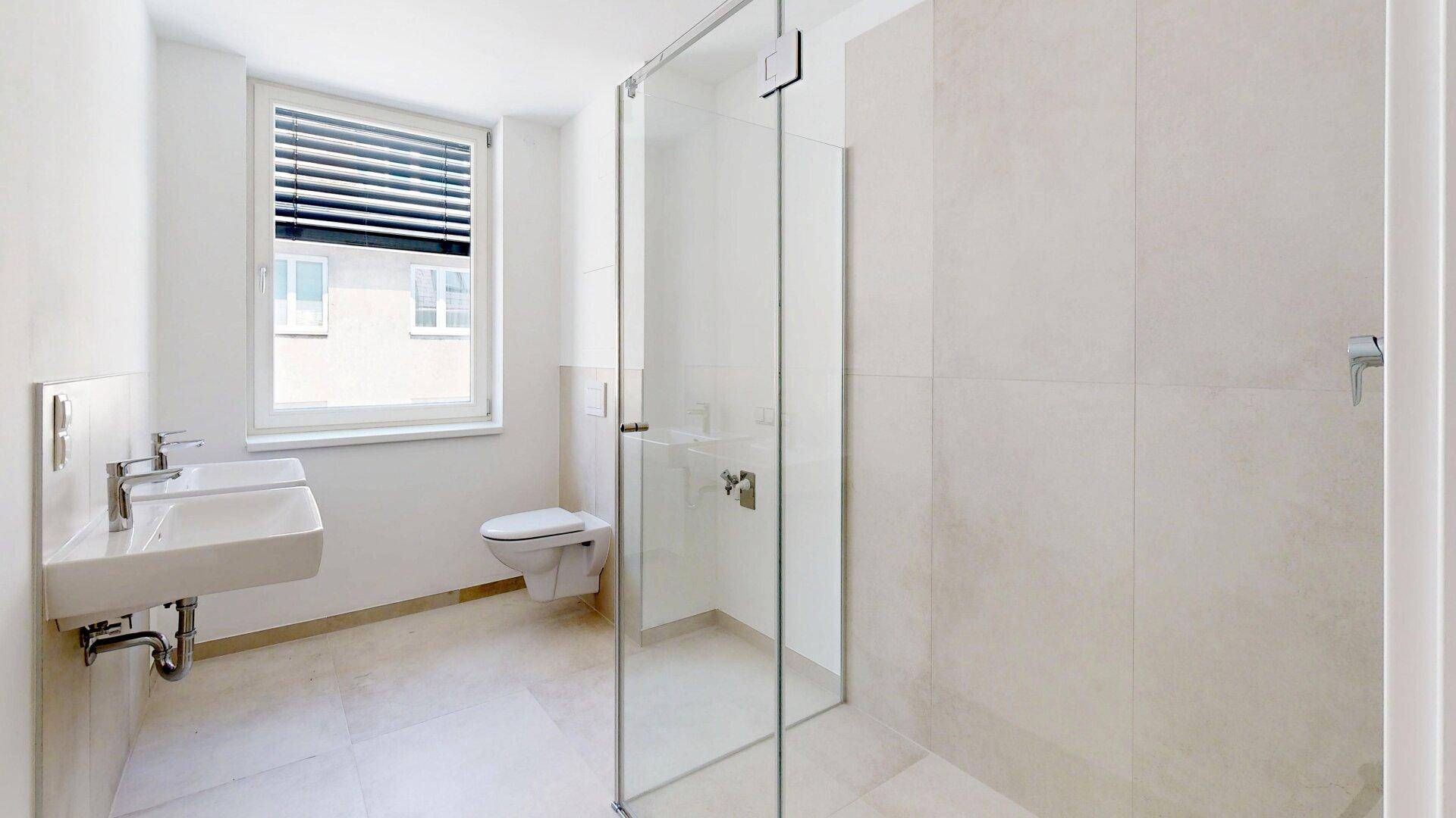 Helles Badezimmer mit ebenerdiger Dusche, wandhängendem WC und Fenster, moderne Ausstattung.