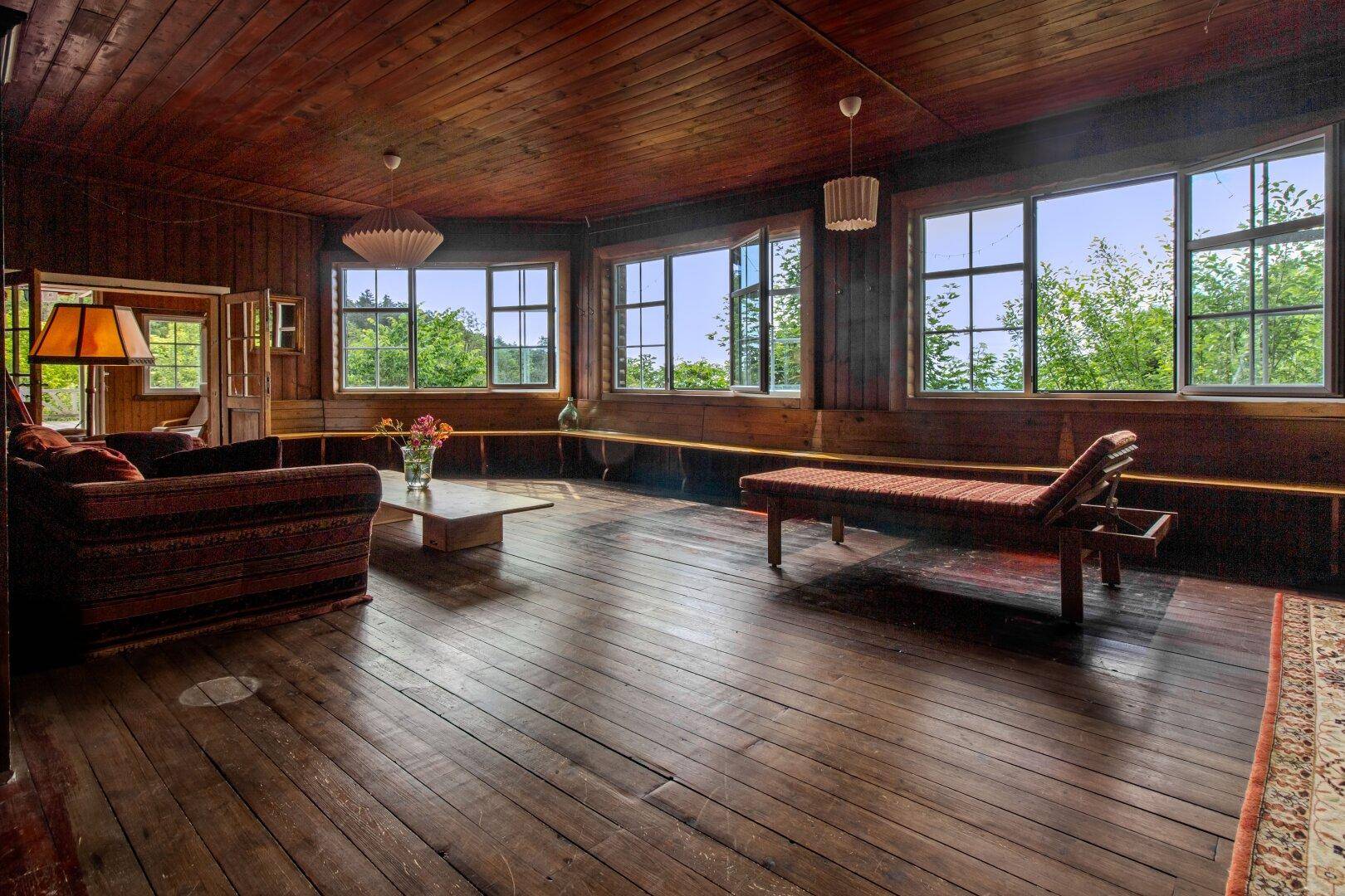 Gemütlicher Wohnbereich mit Holzboden, bequemen Sofas und weitem Blick in die Natur.
