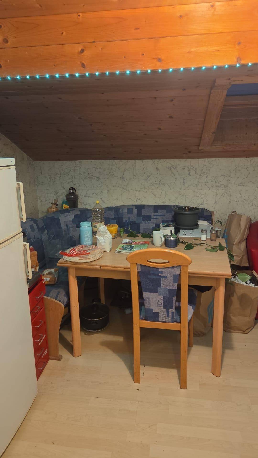 Essbereich mit Holzbalkendecke, Dachschräge und Esstisch, angrenzend an eine gemütliche Sitzecke.