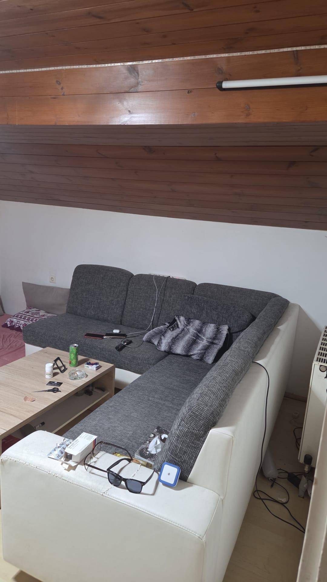 Wohnzimmer im Dachgeschoss mit großer Eckcouch, Couchtisch und charakteristischer Holzbalkendecke.