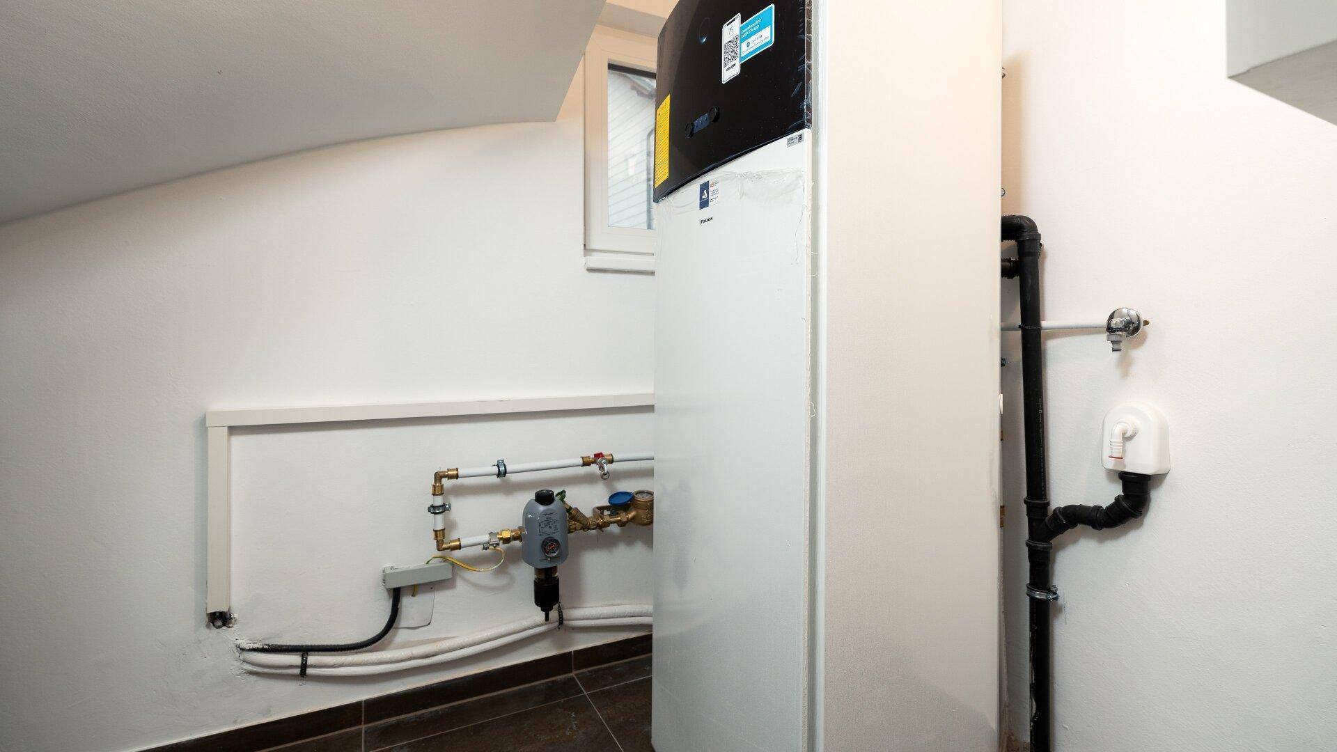 Technikraum mit Wärmepumpe und sichtbaren Installationen, sorgt für effiziente Heizung.