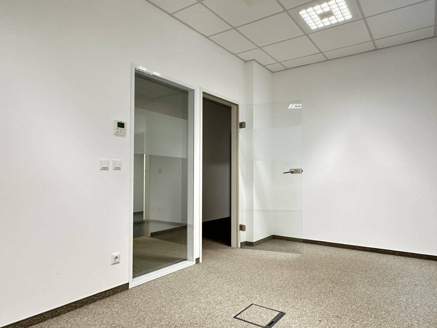Büro mit moderner Glastür und Glaswand, ausgestattet mit strapazierfähigem Terrazzoboden.