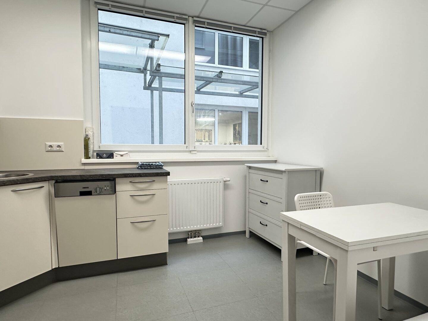 Helle Küchenzeile mit kleinem Esstisch und Stuhl, ideal für Pausen und schnelle Mahlzeiten.
