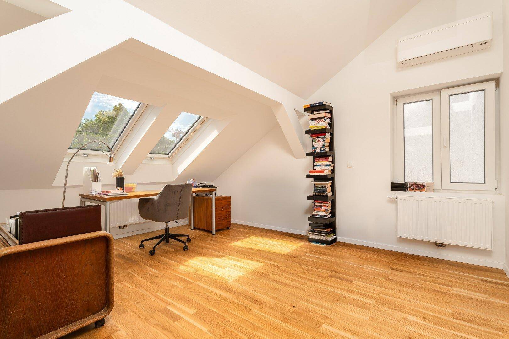 Helles Arbeitszimmer im Dachgeschoss mit Dachfenstern, Holzboden und Klimaanlage.