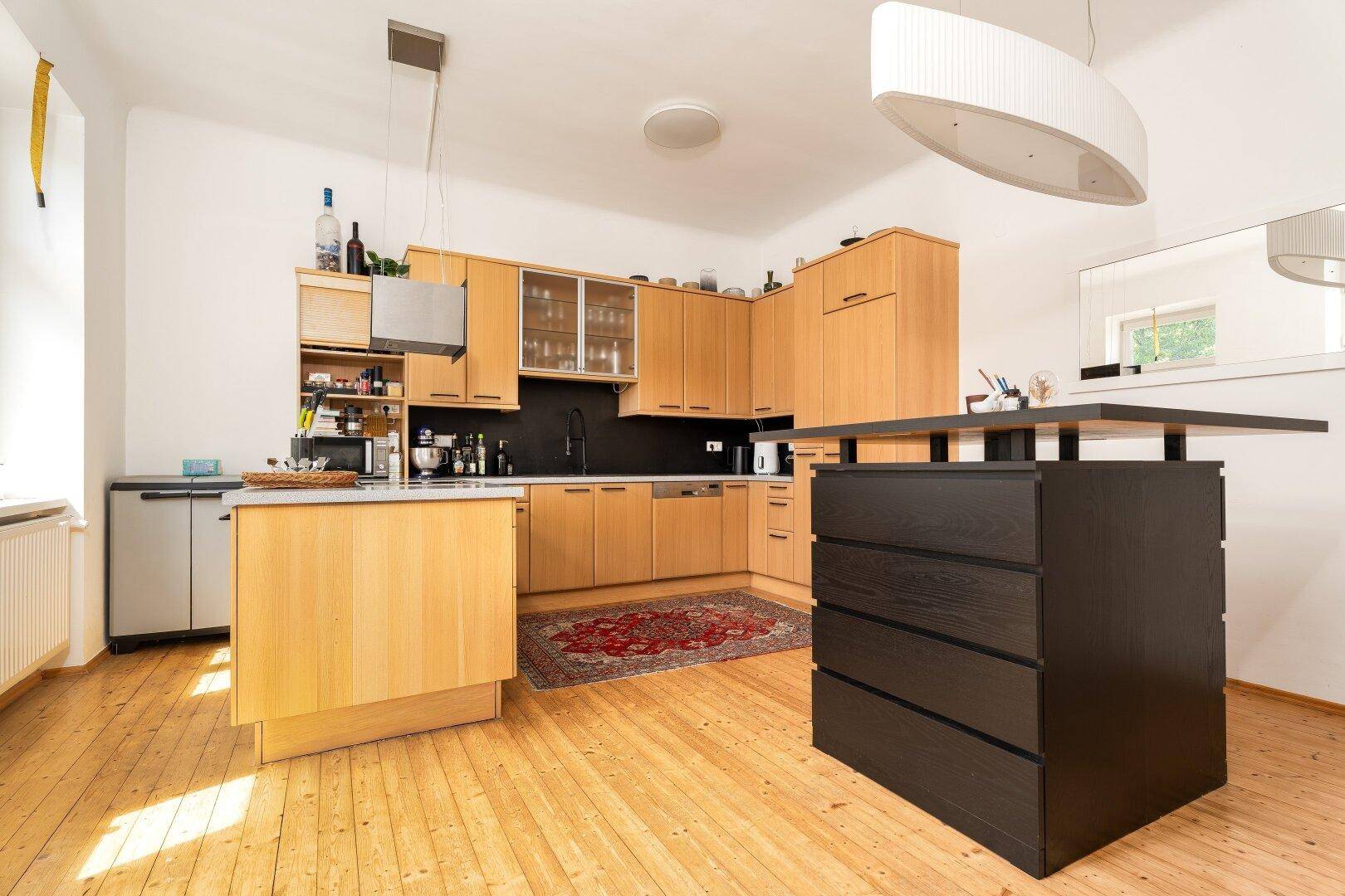 Geräumige Holzküche mit Kücheninsel, modernen Geräten und viel Tageslicht.