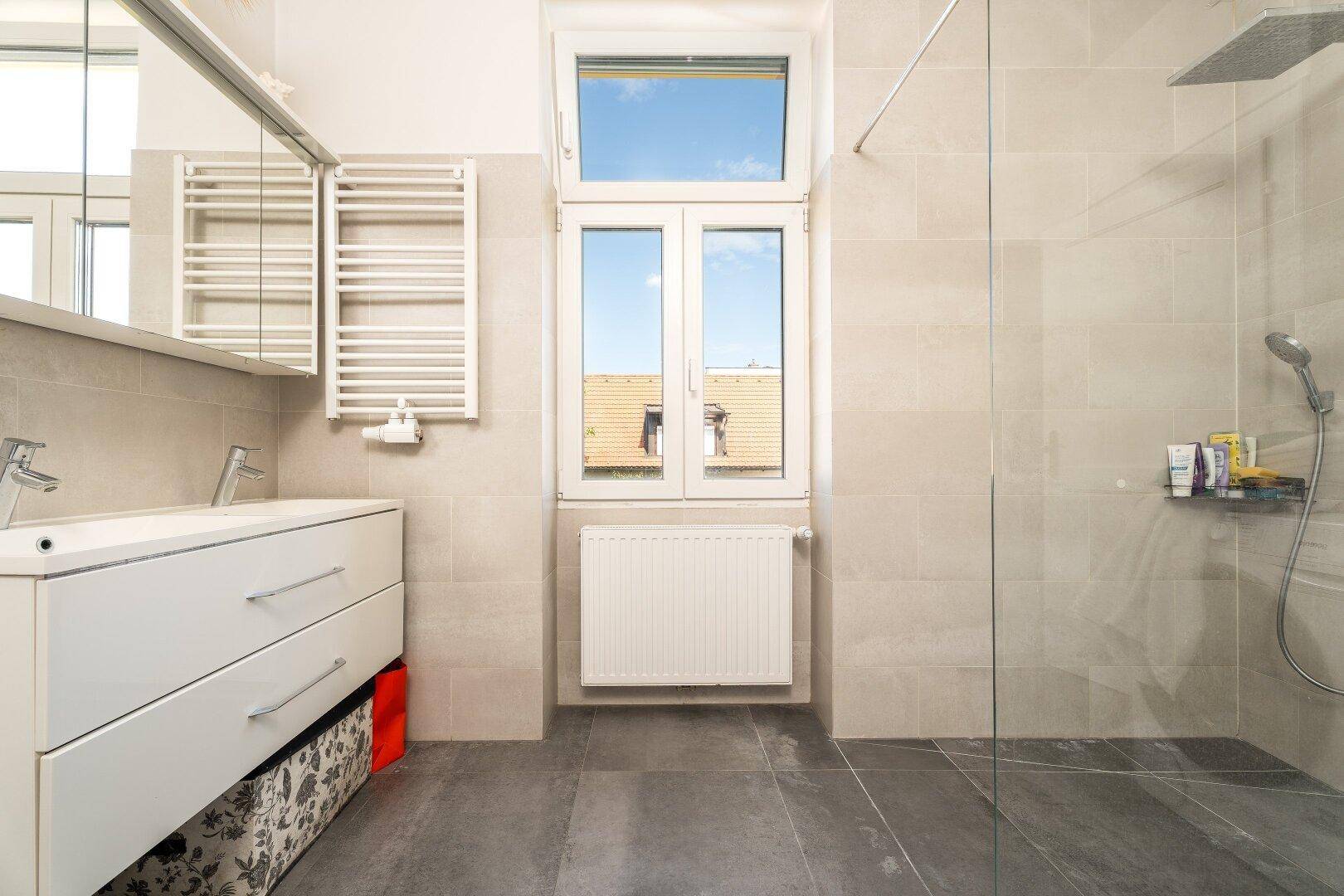 Modernes Badezimmer mit ebenerdiger Dusche, großem Fenster und beheiztem Handtuchhalter.