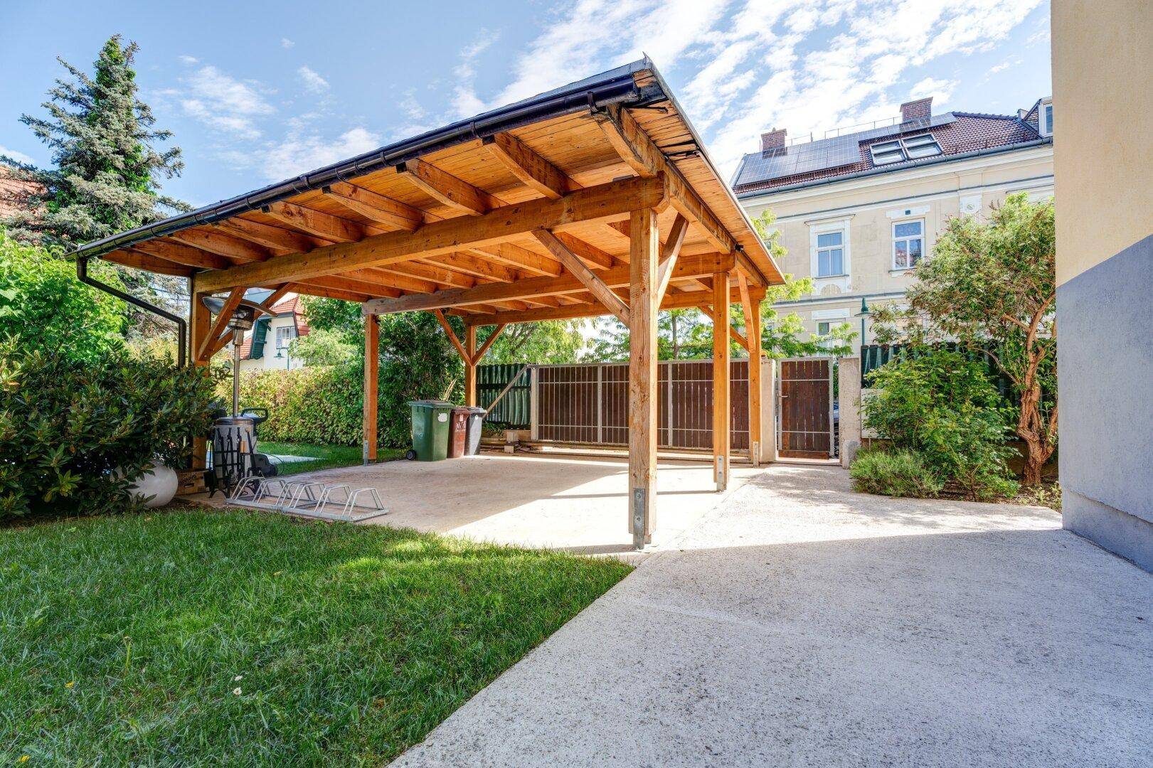 Geräumiger Holzcarport mit angrenzender Grünfläche und Zufahrt.