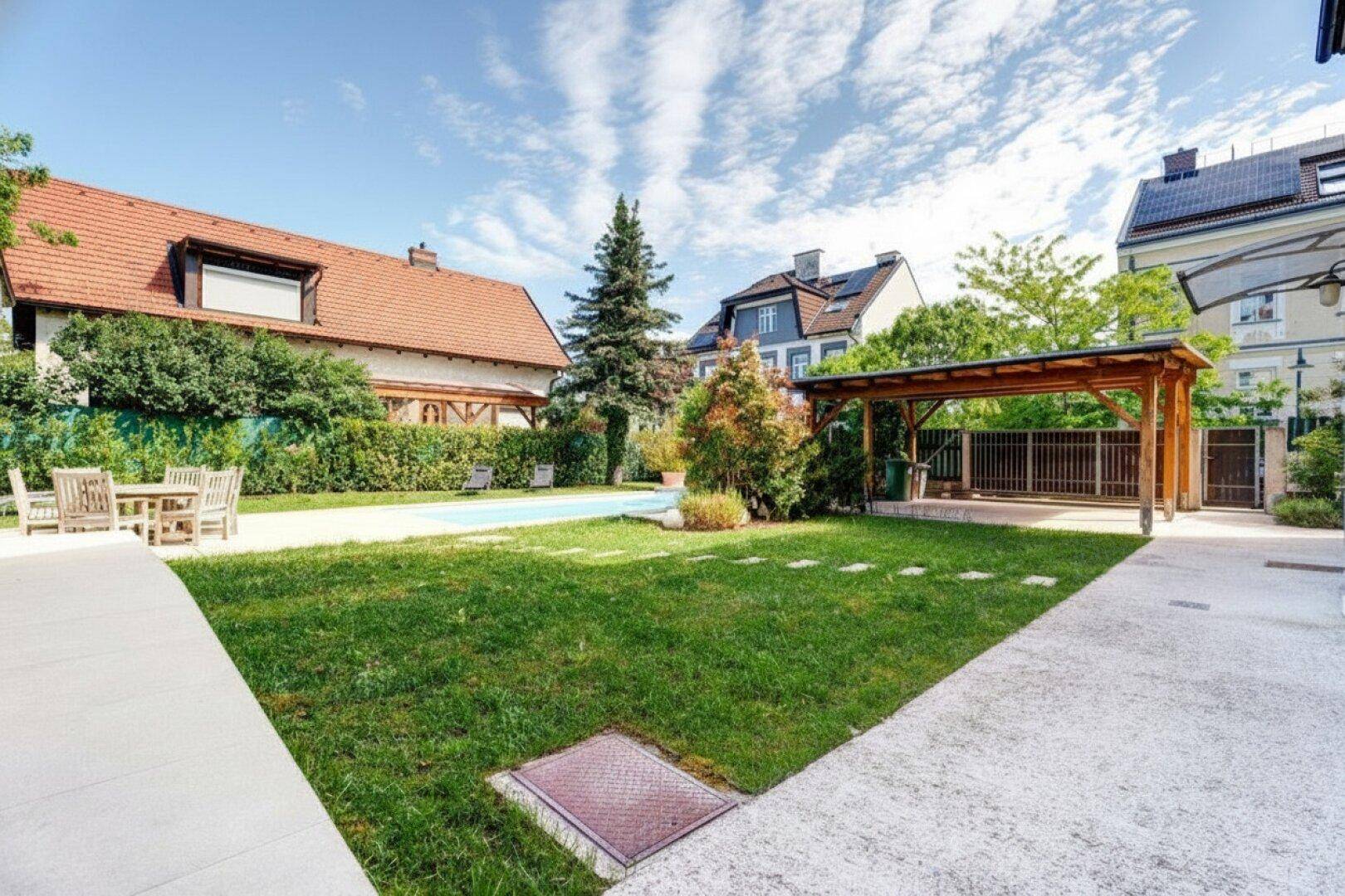 Weitläufiger Garten mit Rasenfläche, überdachtem Bereich und Essplatz im Freien.