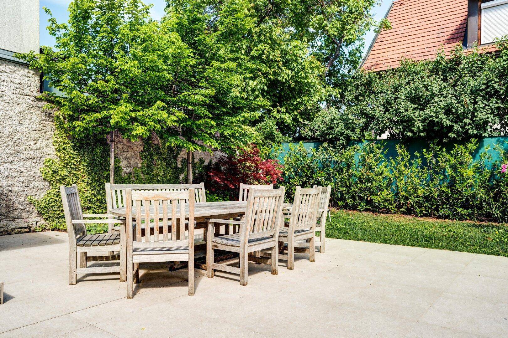 Gemütlicher Essbereich im Freien auf einer gepflasterten Terrasse, umgeben von grüner Vegetation.