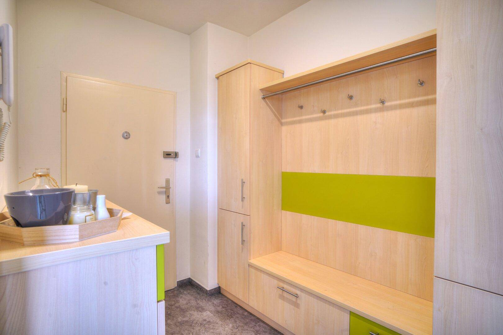 Eingangsbereich mit praktischen Holzmöbeln, Garderobe und Stauraum.