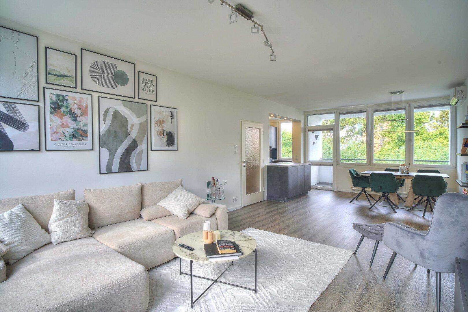 Offener Wohn- und Essbereich mit modernem Sofa, Kunstwerken und Zugang zur Küche.