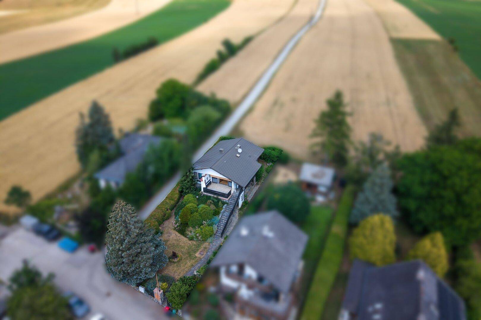 Vogelperspektive des Hauses mit gepflegtem Garten und weiten Feldern im Hintergrund.